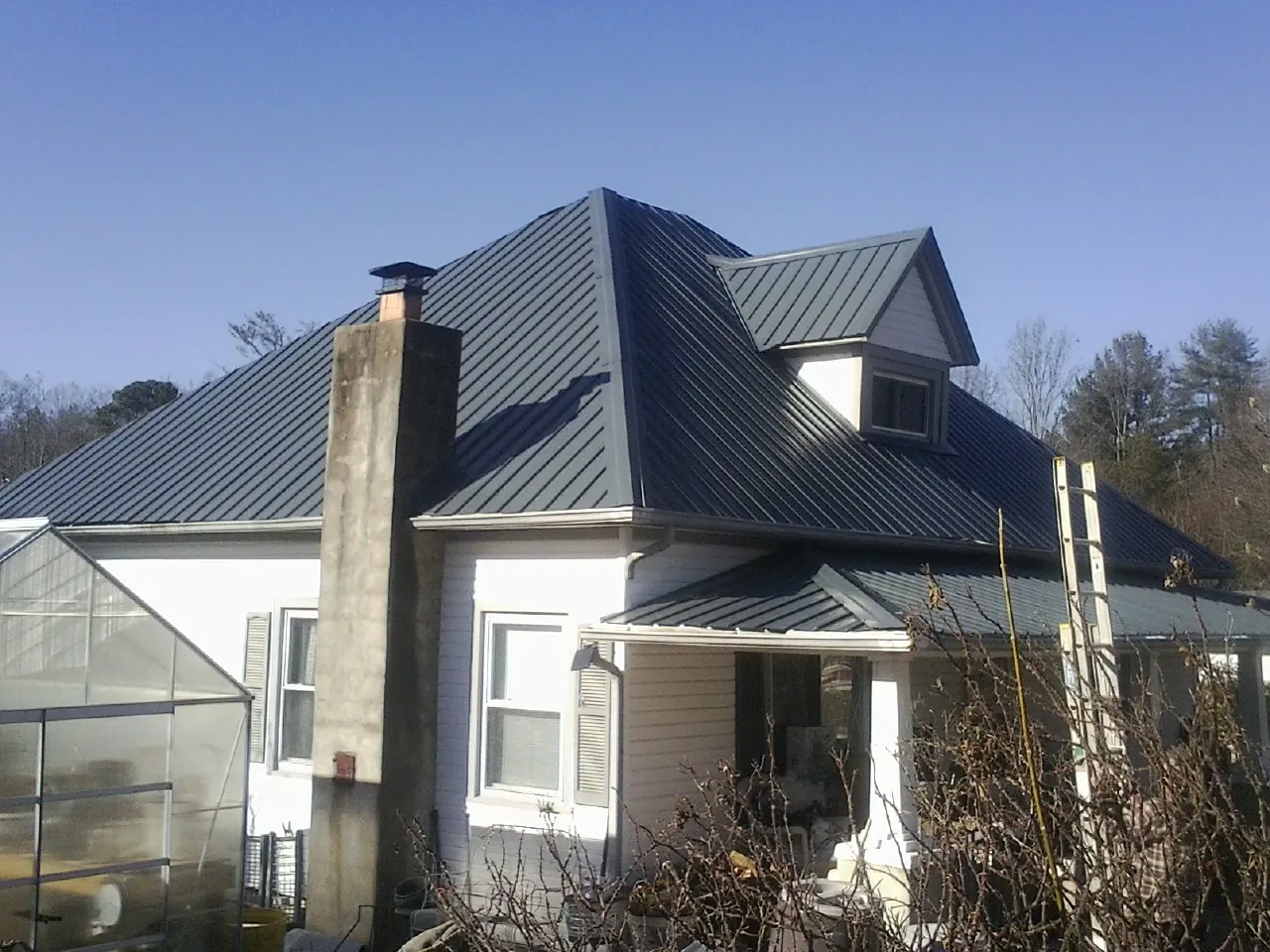 Dark blue standing seam metal roof on a white farmhouse with dormer — Slate & Tile Roof Repair by Roofing Brothers in Newton Upper Falls