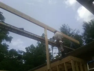 Carpenter setting a ridge beam over a new addition frame in Newton Upper Falls