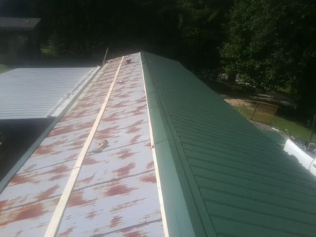 Old rusted panels beside newly installed green metal roofing — Wind Damage Roof Repair by Roofing Brothers in Newton Upper Falls