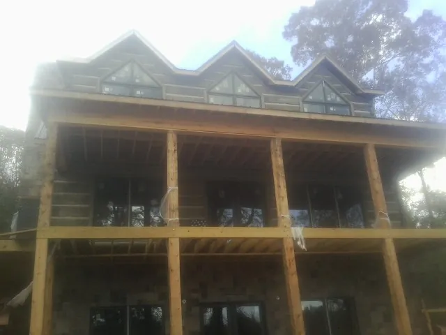 Dormers and porch framing on a large log home under construction — Roof Coating work by our crew in Newton Upper Falls
