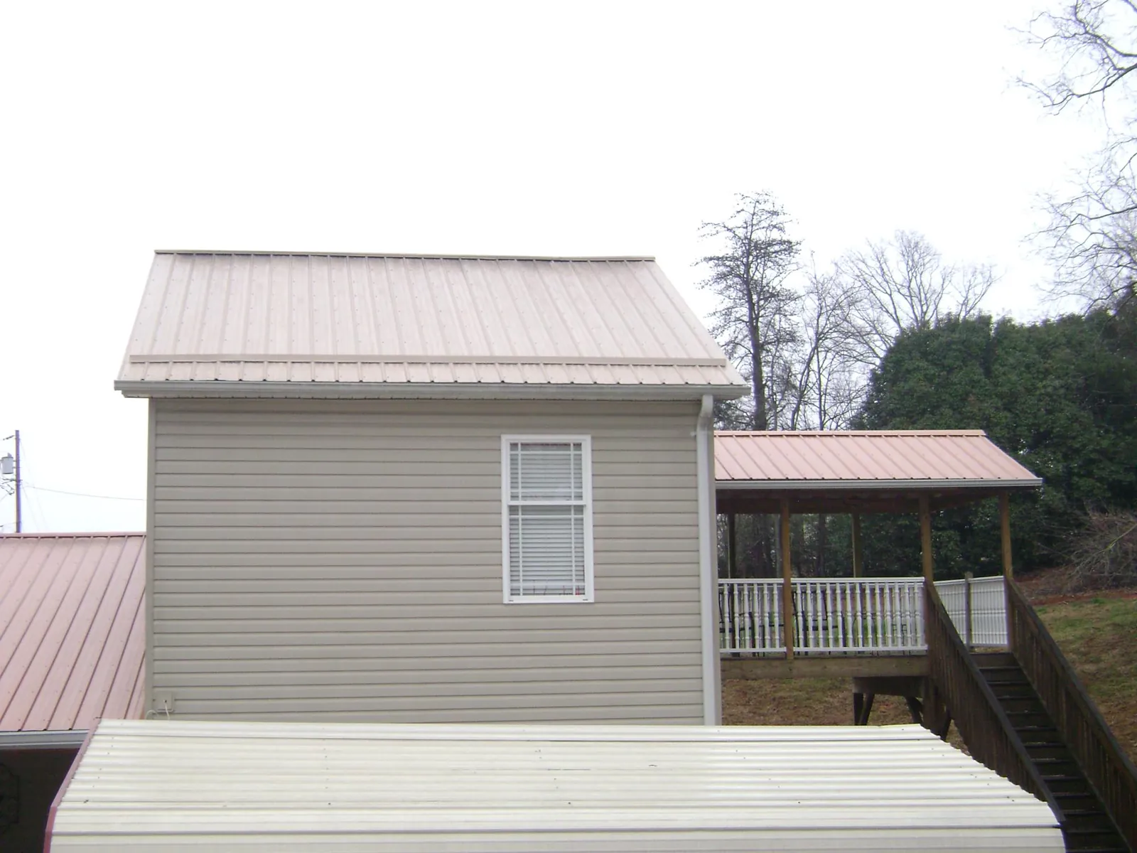 Tan metal roofs on a two story addition and attached porch, from a Roof Replacement job in Newton Upper Falls